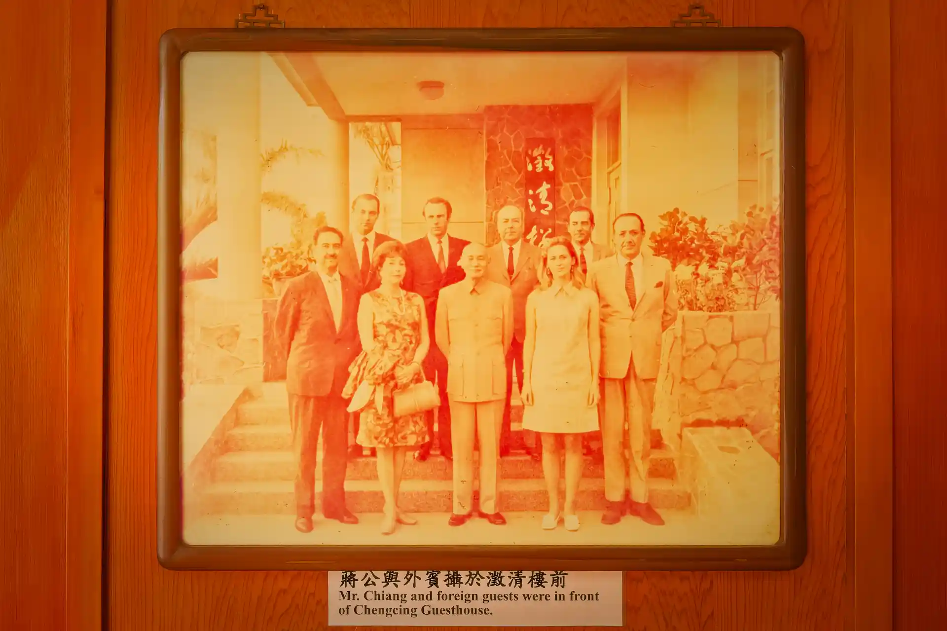 A faded photo showing a group of nine people standing on the steps of Chiang Kai-Shek’s winter residence. Chiang Kai-Shek is standing in the middle of the front row. ALl other people appear to be foreign and wearing 1960s or 1970s clothes.