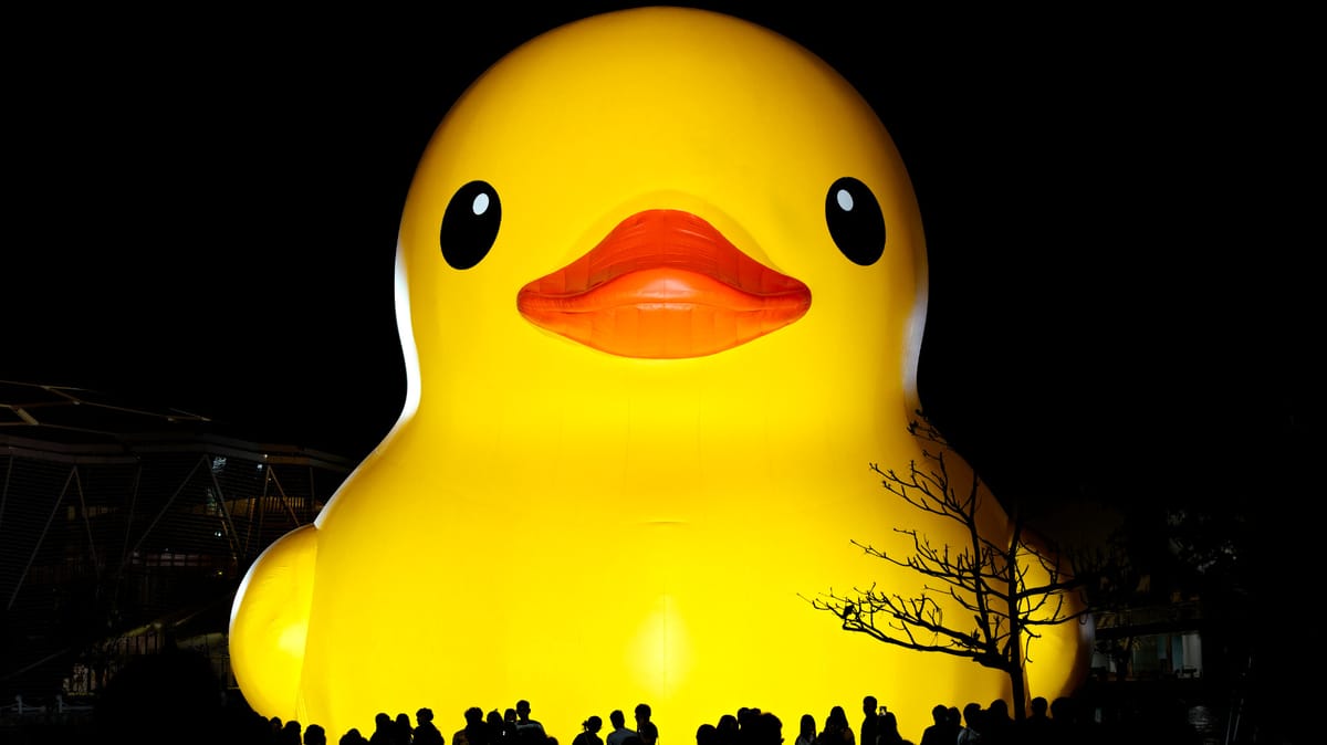 Frontal view of a large rubber duck moored on Kaohsiung Harbor at night.