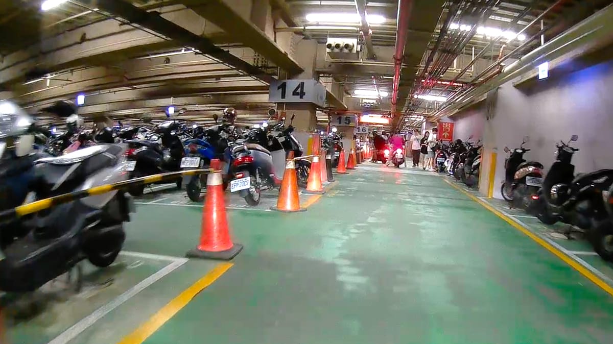 Still frame from motorcycle dashcam footage of an underground scooter parking lot at Dream Mall, Kaohsiung, Taiwan.