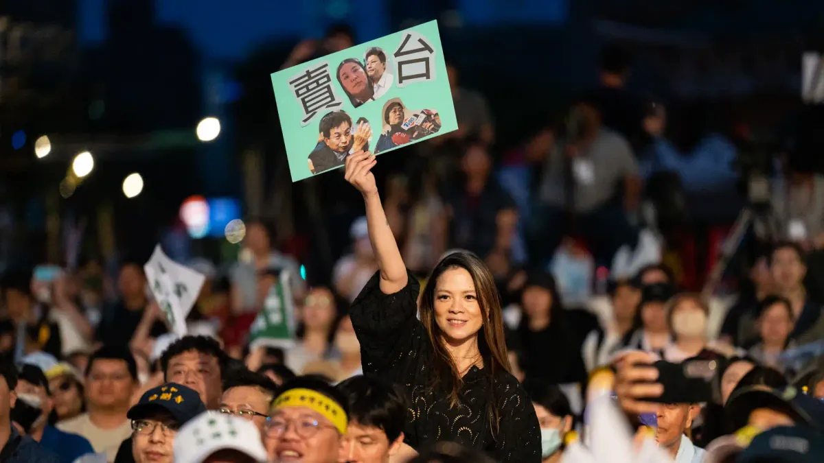 A protester hiding a sign at a political rally in Taiwan.