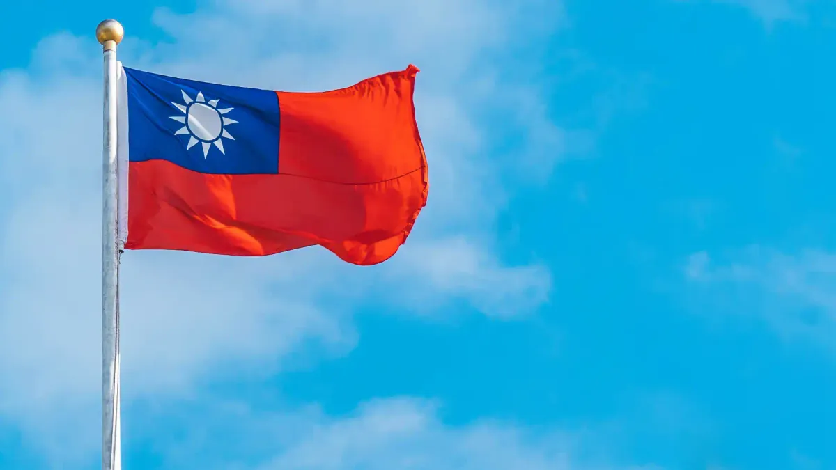 The flag of the Republic of China, commonly known as the flag of Taiwan, against a sunny blue sky.