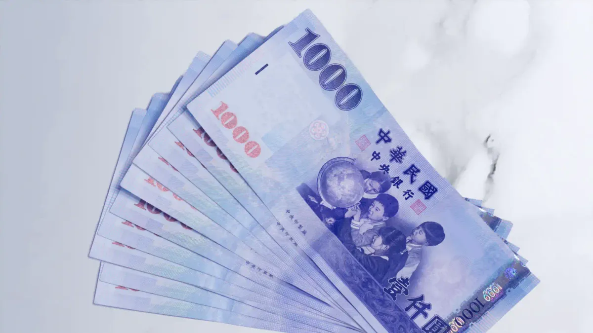 Ten $1,000 New Taiwan Dollar bank notes fanned out on a marble table.